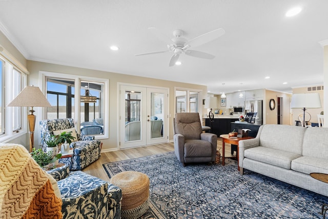 living room with crown molding, french doors, ceiling fan, and light wood-type flooring