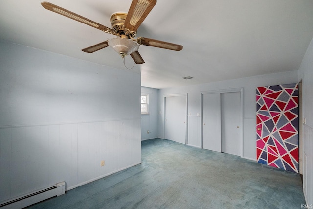 interior space with carpet flooring, wainscoting, a baseboard heating unit, and a ceiling fan