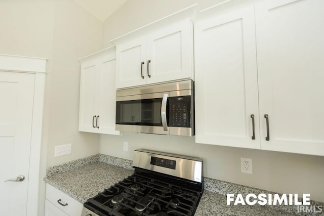 kitchen featuring light stone counters, stainless steel appliances, and white cabinets