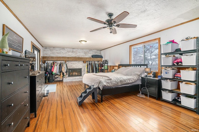 bedroom featuring ornamental molding, a fireplace, and light hardwood / wood-style floors