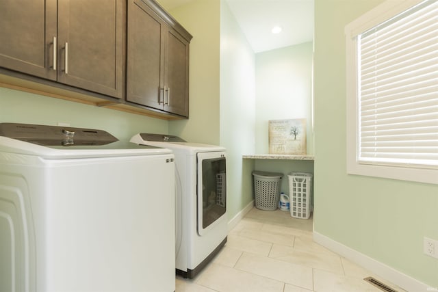 laundry room featuring cabinets, washer and dryer, and light tile patterned floors