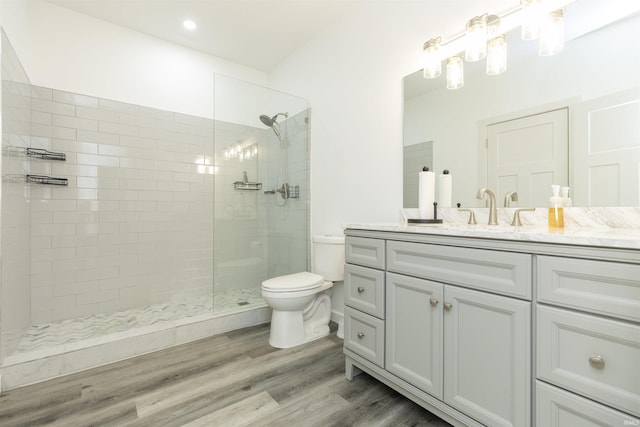 bathroom featuring tiled shower, wood-type flooring, toilet, and vanity