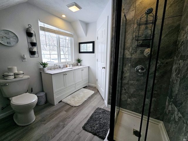 bathroom with hardwood / wood-style floors, a shower with shower door, vanity, toilet, and a textured ceiling