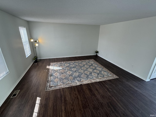 empty room with dark hardwood / wood-style floors and a textured ceiling