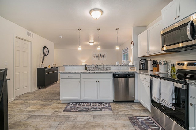 kitchen with sink, appliances with stainless steel finishes, pendant lighting, light stone countertops, and white cabinets