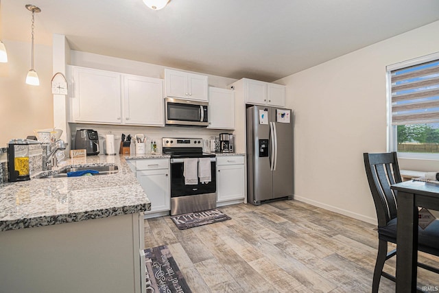 kitchen with sink, appliances with stainless steel finishes, white cabinetry, light stone countertops, and decorative light fixtures