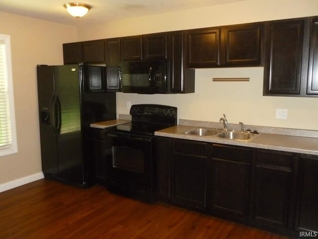 kitchen with sink, dark brown cabinets, dark wood-type flooring, and black appliances