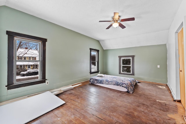 unfurnished bedroom with wood-type flooring, lofted ceiling, ceiling fan, and a textured ceiling