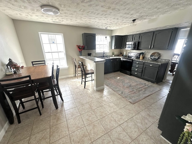 kitchen with sink, appliances with stainless steel finishes, a textured ceiling, and light stone counters