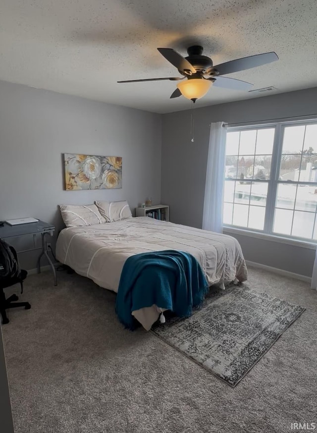 bedroom featuring ceiling fan, carpet floors, and a textured ceiling