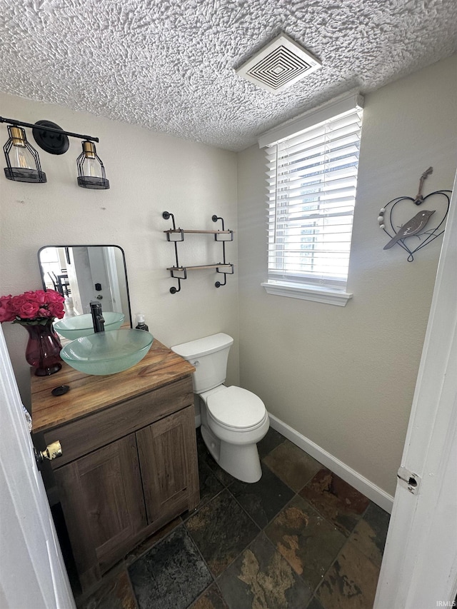 bathroom featuring a textured ceiling, toilet, and vanity