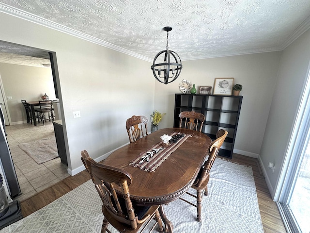 dining area with an inviting chandelier, a textured ceiling, light hardwood / wood-style flooring, and ornamental molding