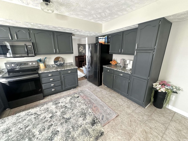 kitchen featuring black fridge, electric range oven, light stone countertops, and a textured ceiling