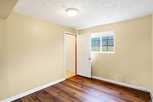 empty room featuring dark hardwood / wood-style flooring and a textured ceiling