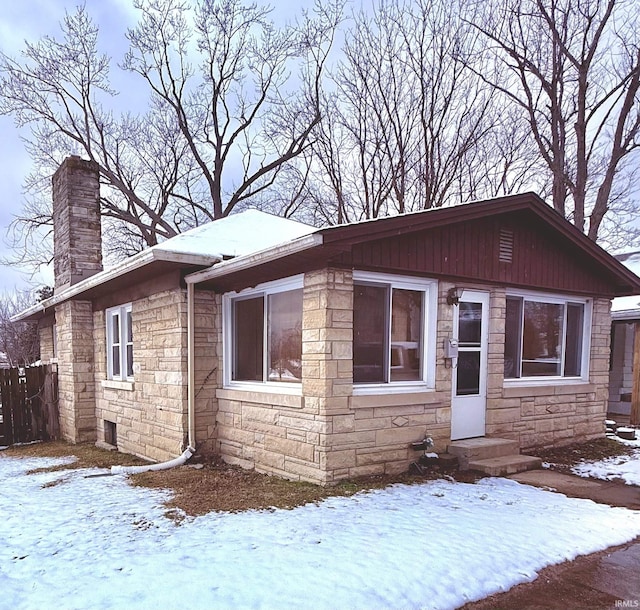 view of front of house with stone siding and a chimney