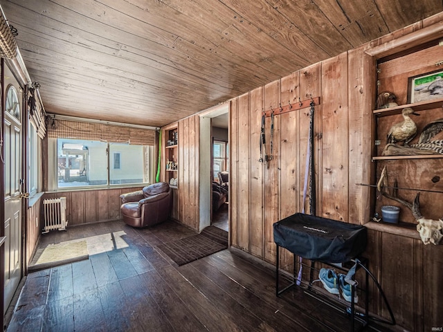 miscellaneous room with wooden walls, dark wood-style flooring, wooden ceiling, and radiator