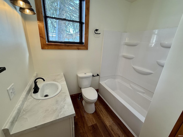 full bath with toilet, wood finished floors, vanity, and baseboards