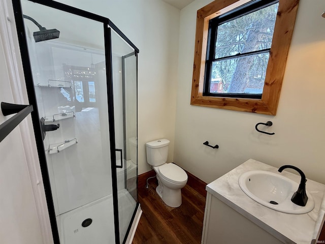 bathroom featuring toilet, a stall shower, wood finished floors, and vanity