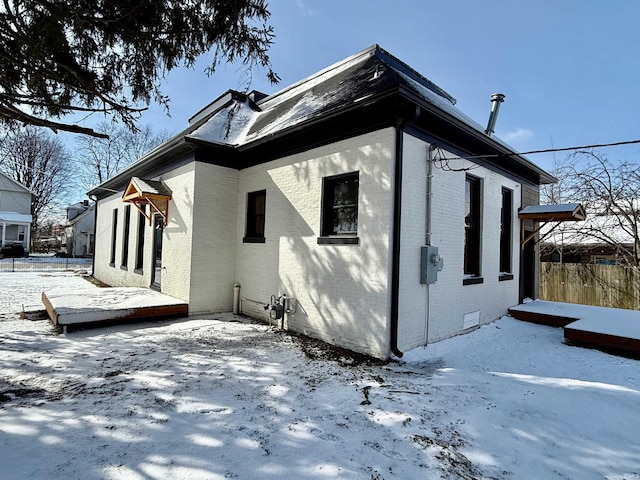 snow covered property with crawl space and brick siding