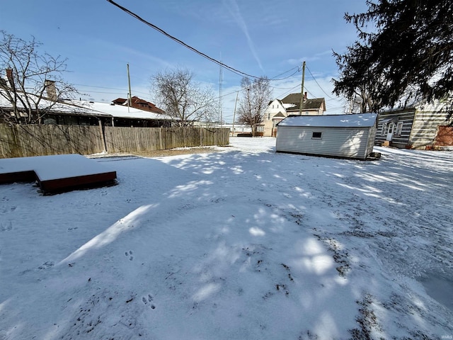 yard covered in snow with a shed, fence, and an outbuilding