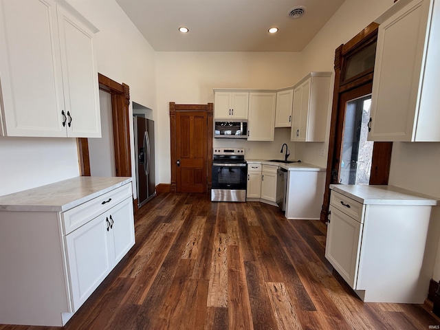 kitchen featuring visible vents, dark wood-style flooring, stainless steel appliances, light countertops, and a sink