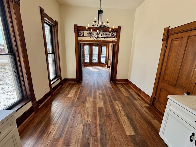 interior space with dark wood-type flooring, french doors, a chandelier, and baseboards