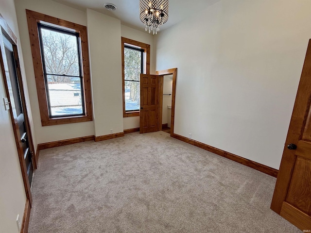 unfurnished room featuring light carpet, an inviting chandelier, baseboards, and visible vents