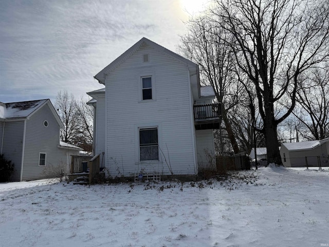 snow covered back of property with a wooden deck