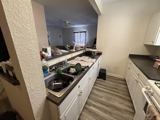 kitchen featuring dark hardwood / wood-style floors, white cabinetry, sink, kitchen peninsula, and white gas stove