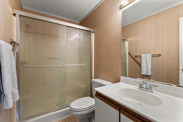 bathroom featuring toilet, vanity, a shower with shower door, and ornamental molding