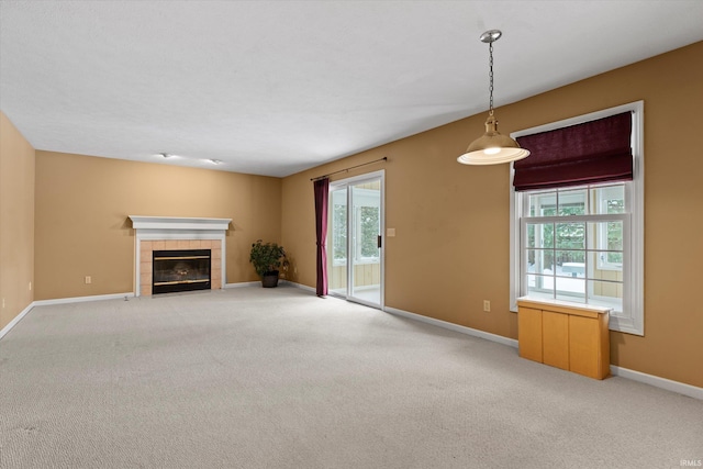 unfurnished living room featuring a tile fireplace and light colored carpet