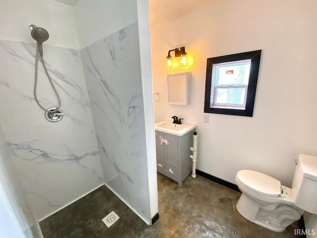 bathroom with toilet, a tile shower, and vanity