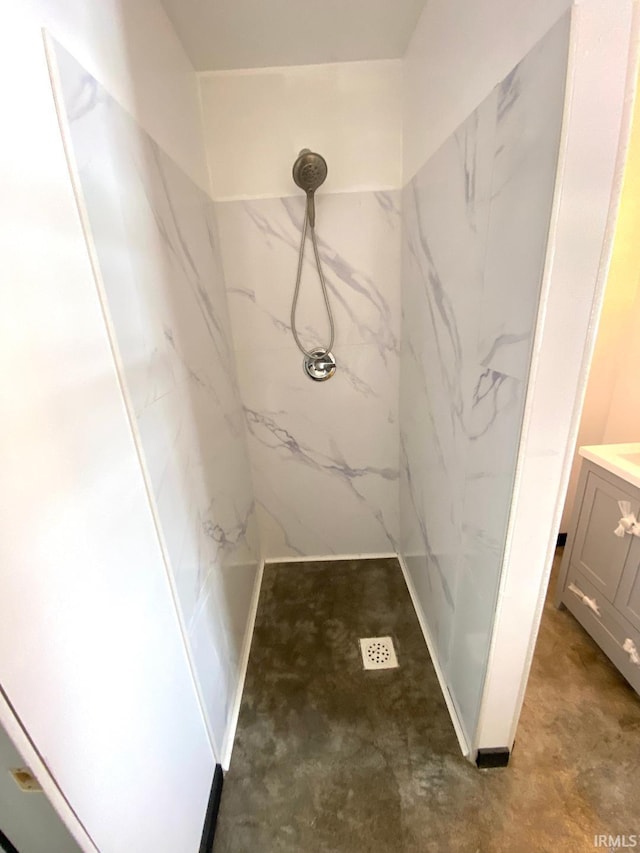 bathroom with a tile shower and vanity