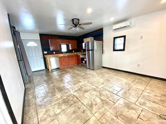 kitchen featuring appliances with stainless steel finishes, ceiling fan, a wall unit AC, and sink