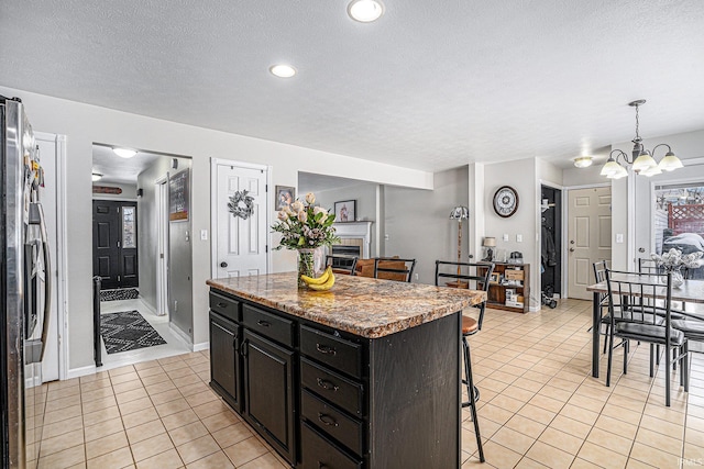 kitchen featuring a center island, decorative light fixtures, stainless steel fridge, light tile patterned floors, and a kitchen breakfast bar
