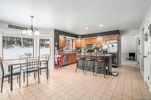 kitchen with stainless steel appliances, a kitchen island, a breakfast bar area, light tile patterned flooring, and pendant lighting