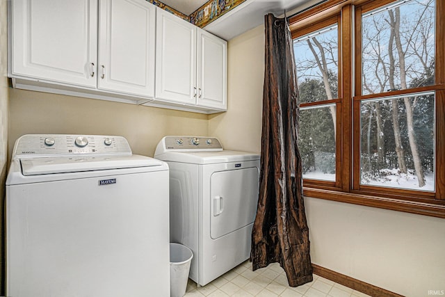 clothes washing area with washer and clothes dryer and cabinets