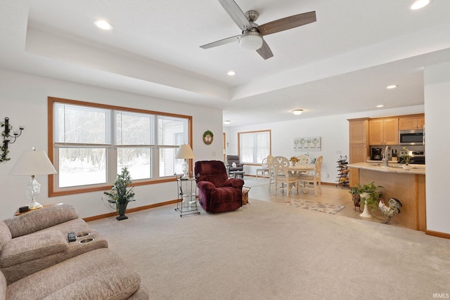 living room featuring ceiling fan, a raised ceiling, and light colored carpet