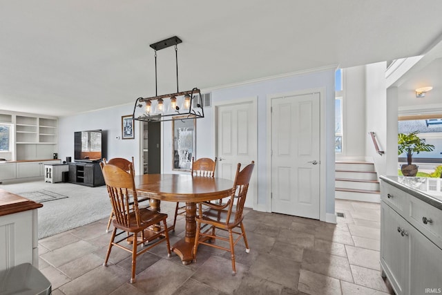 dining area featuring built in features, ornamental molding, and a notable chandelier