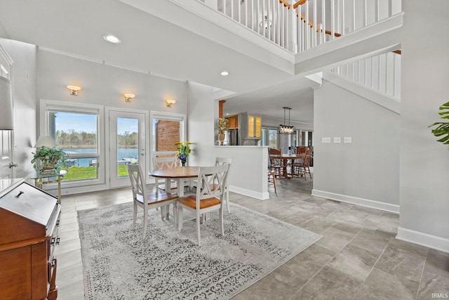 dining room featuring a water view and a towering ceiling