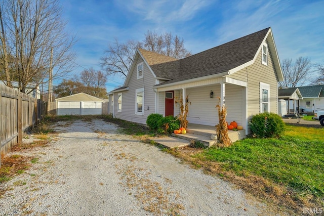 view of side of home with a garage, an outdoor structure, and a porch