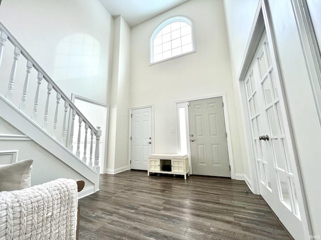 foyer with dark wood-type flooring and a towering ceiling