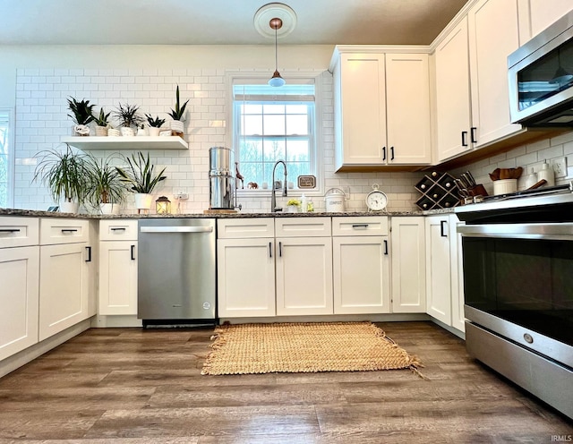 kitchen featuring white cabinetry, appliances with stainless steel finishes, dark stone counters, and decorative light fixtures