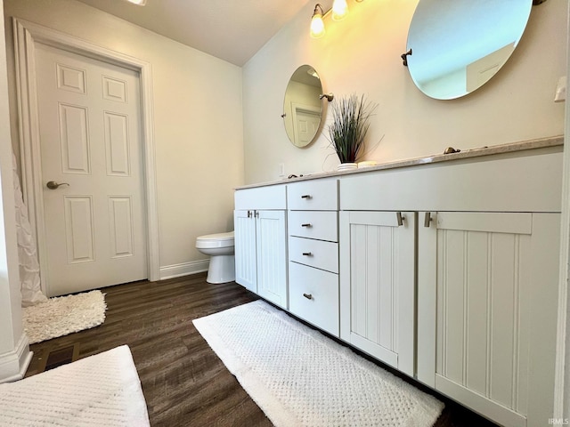 bathroom with toilet, vanity, and wood-type flooring