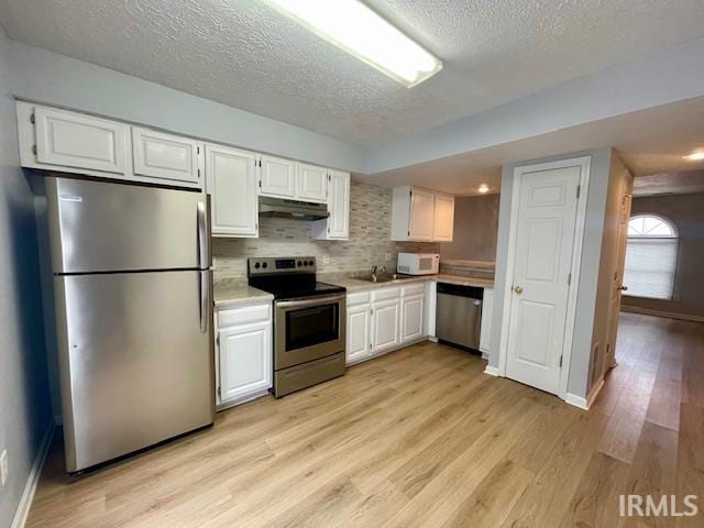 kitchen featuring light hardwood / wood-style flooring, sink, backsplash, appliances with stainless steel finishes, and white cabinets