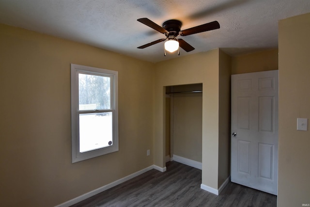 unfurnished bedroom featuring ceiling fan, dark hardwood / wood-style floors, a textured ceiling, and a closet