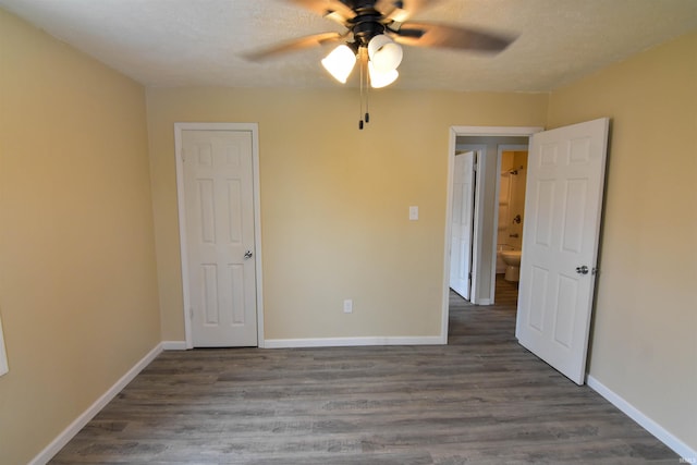 unfurnished bedroom with dark hardwood / wood-style flooring, ceiling fan, and a textured ceiling