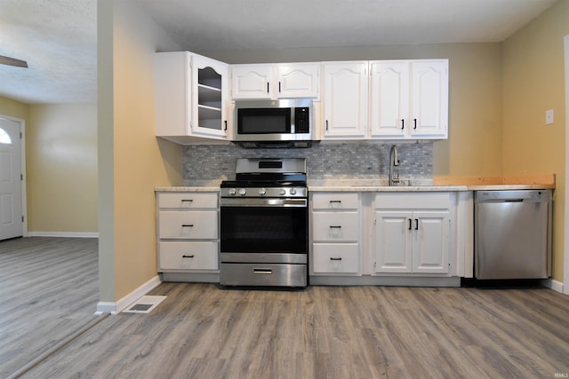 kitchen with white cabinets, appliances with stainless steel finishes, sink, and decorative backsplash