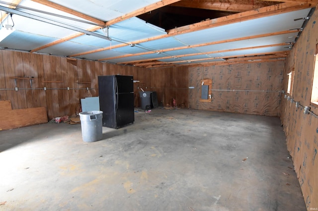 interior space with electric panel and black refrigerator