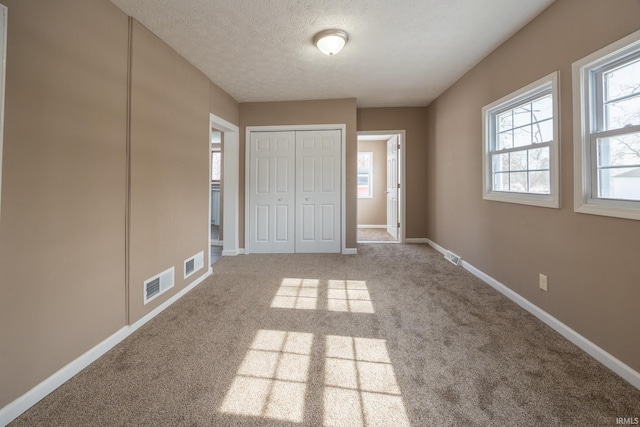 unfurnished bedroom featuring a closet, carpet flooring, and a textured ceiling